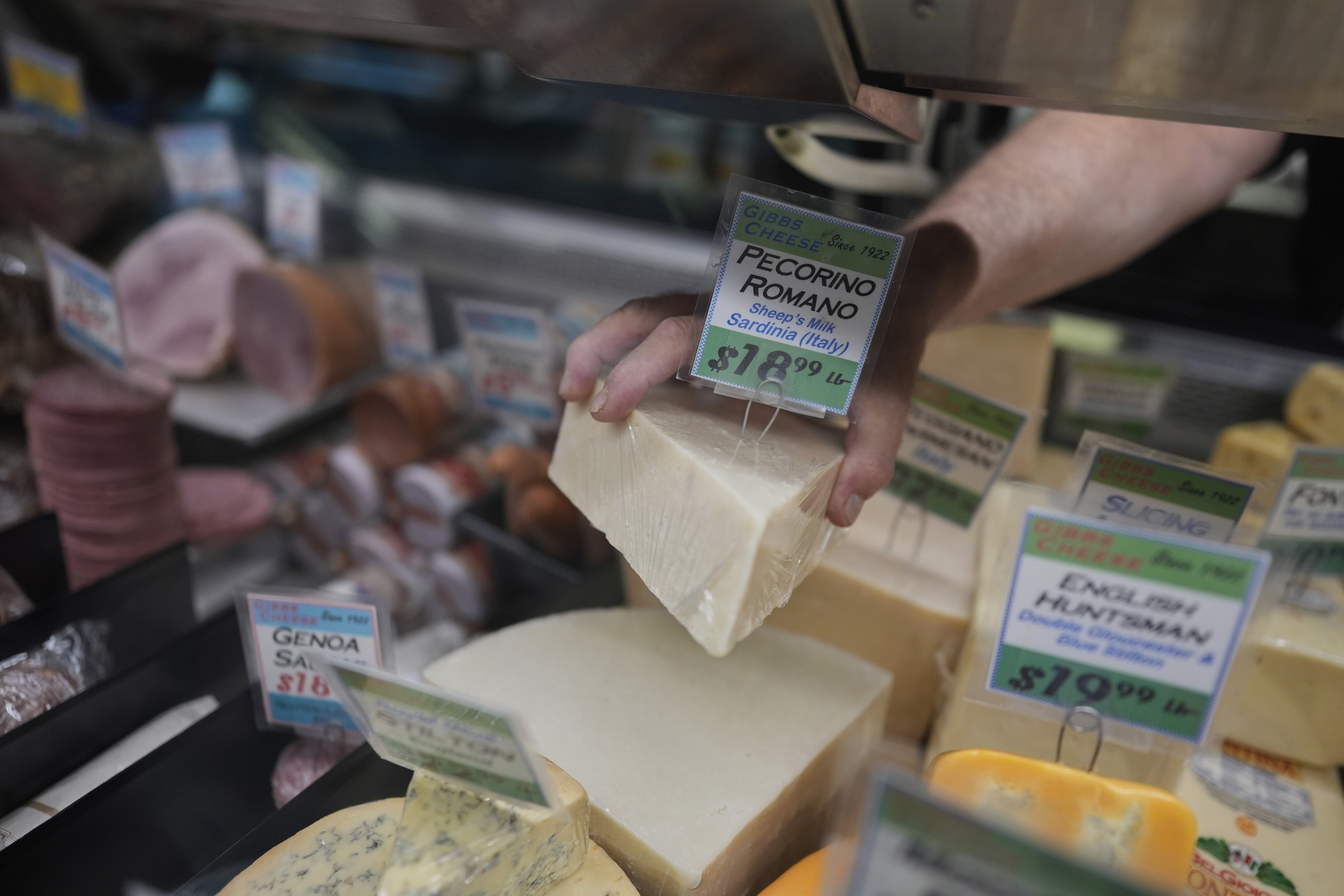 Jeff Gibbs, owner of Gibbs Cheese, reaches for Pecorino Romano cheese imported from Sardinia, Italy, at his shop in Findlay Market, April 3, in Cincinnati.