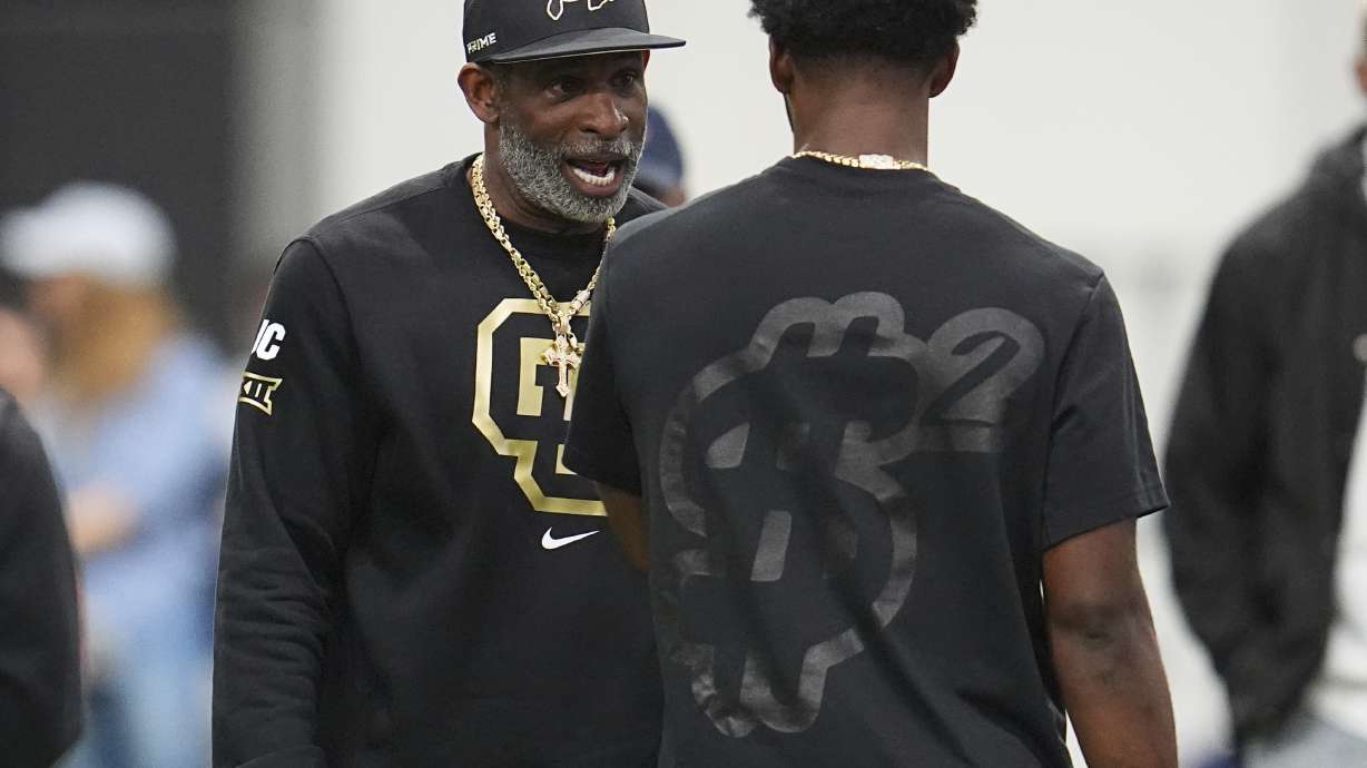 Colorado head coach Deion Sanders, left, talks with his son, quarterback Shedeur Sanders before passing drills at Colorado's NFL football pro day Friday, April 4, 2025, in Boulder, Colo.