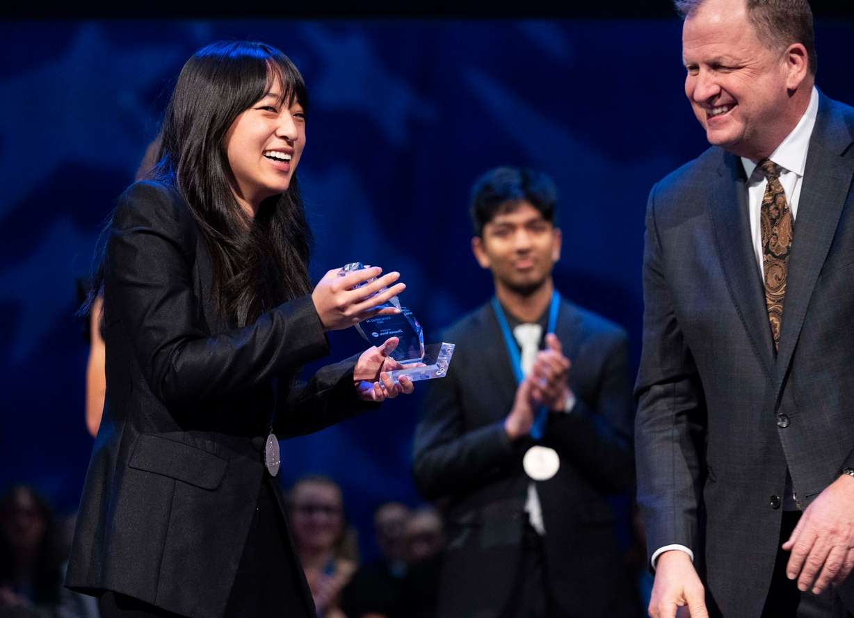 Xiaocheng Ai, of Corner Canyon High School, laughs upon receiving the General Sterling Scholar Award from the president and CEO of Deseret Management Corporation, Jeff Simpson, at the 2025 Sterling Scholar Ceremony at the Conference Center Little Theater in Salt Lake City on Thursday.