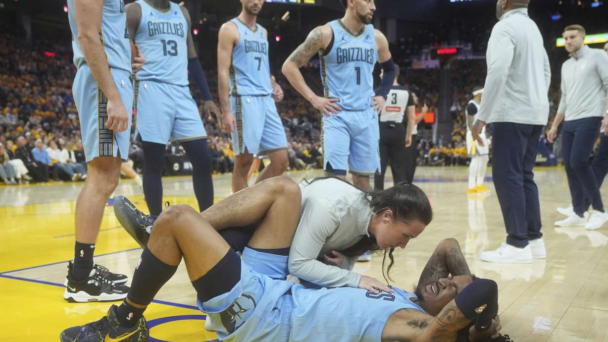 Memphis Grizzlies guard Ja Morant, bottom, reacts after hitting the floor during the second half of an NBA play-in tournament basketball game against the Golden State Warriors in San Francisco, Tuesday, April 15, 2025.