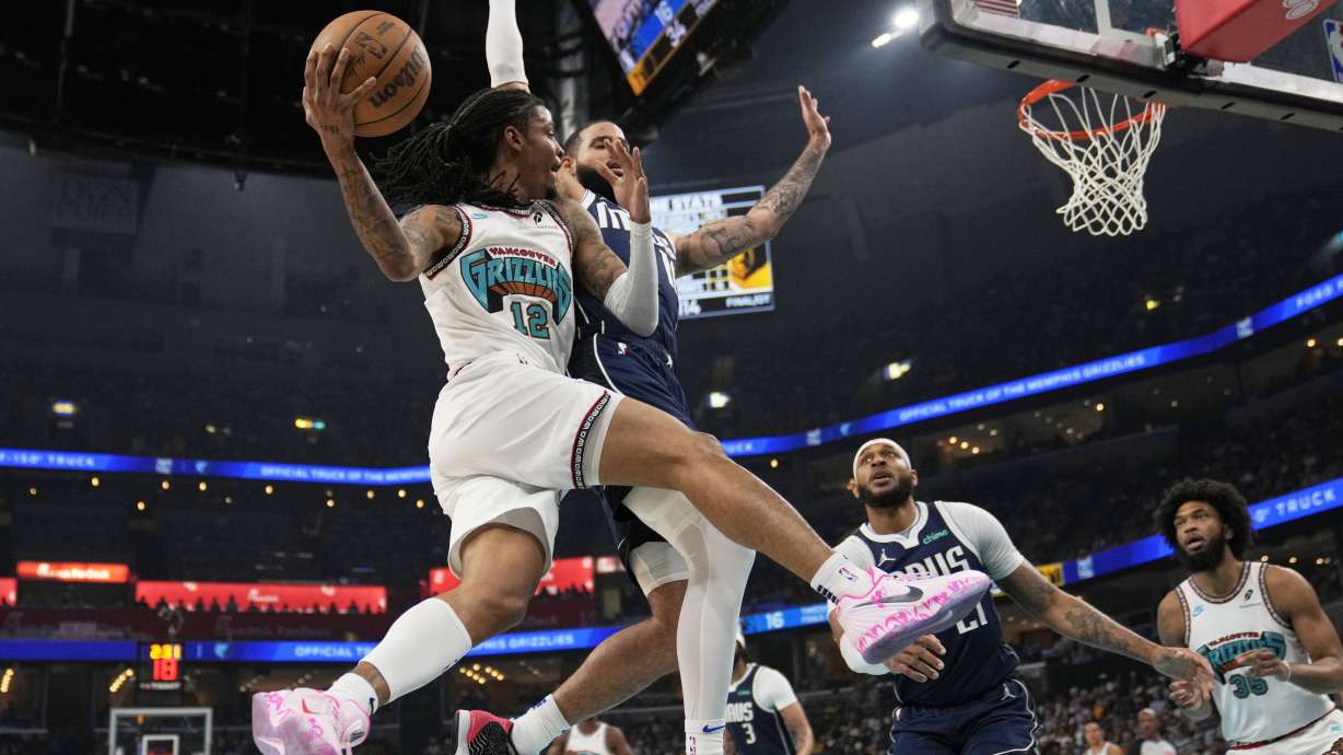 Memphis Grizzlies guard Ja Morant (12)- passes the ball around Dallas Mavericks forward Caleb Martin, right, during the first half of an NBA play-in tournament basketball game Friday, April 18, 2025, in Memphis, Tenn.
