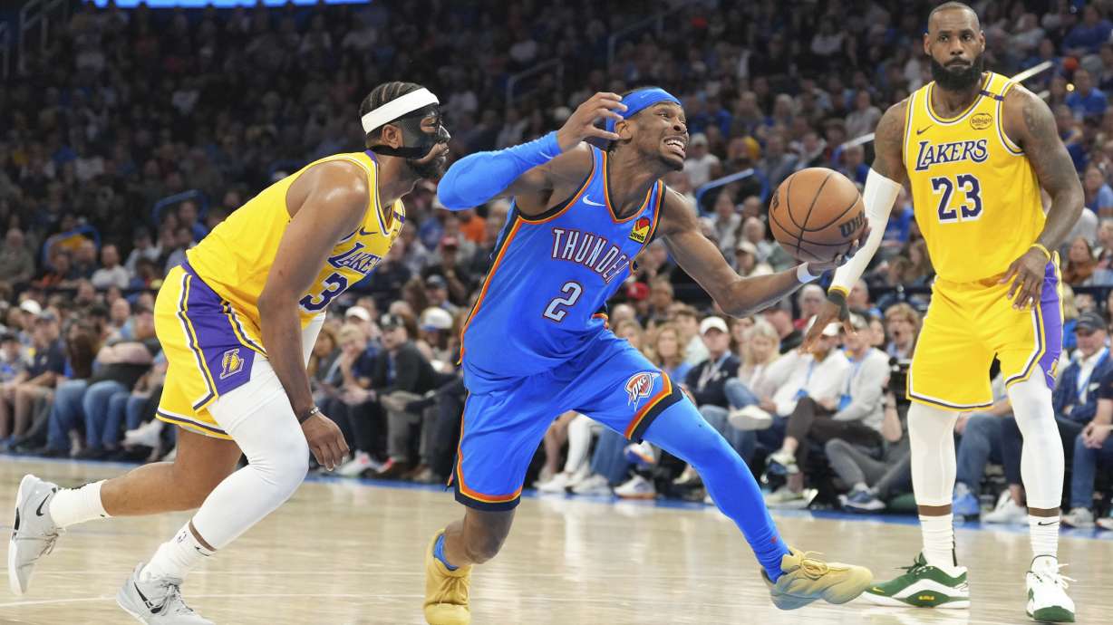 Oklahoma City Thunder guard Shai Gilgeous-Alexander, middle, drives past Los Angeles Lakers guard Jordan Goodwin, left, and forward LeBron James, right, during the second half of an NBA basketball game, Tuesday, April 8, 2025, in Oklahoma City.