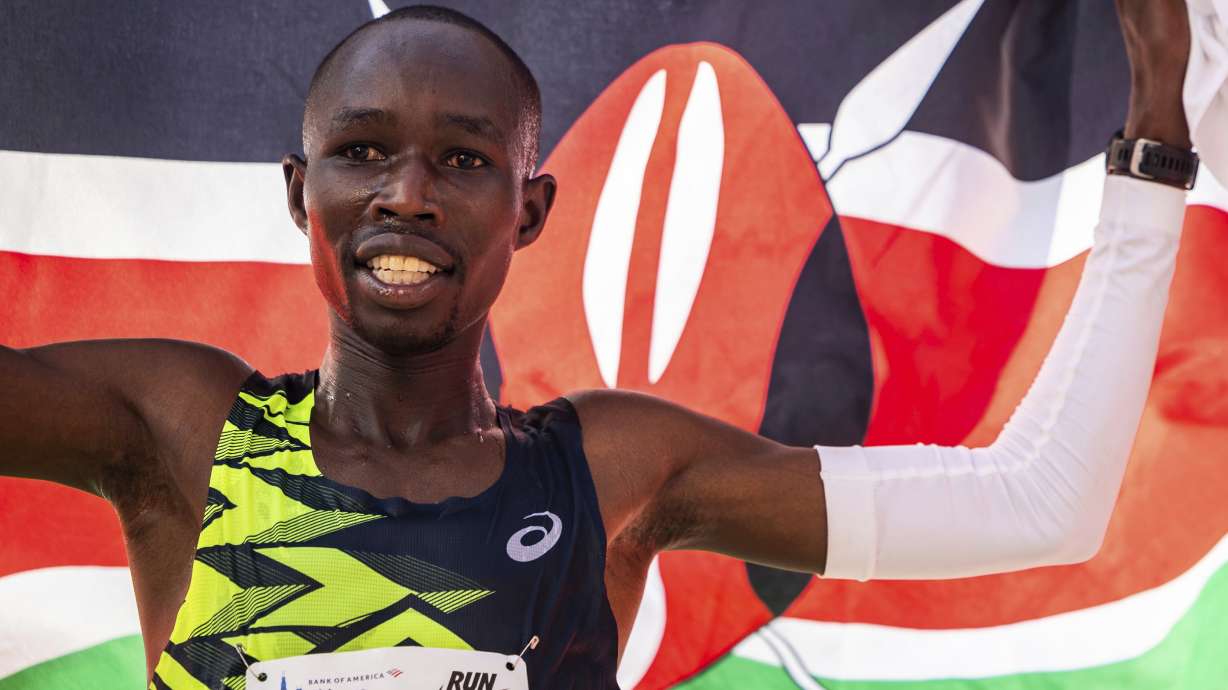 FILE - John Korir, from Kenya, runs with the Kenyan flag after crossing the finish line of the Chicago Marathon to win the professional men's division in Grant Park on Sunday, Oct. 13, 2024.