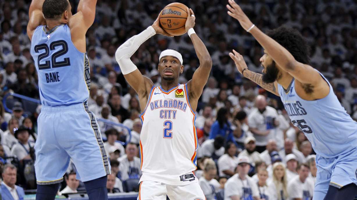 Oklahoma City Thunder guard Shai Gilgeous-Alexander (2) looks to pass between Memphis Grizzlies guard Desmond Bane (22) and forward Marvin Bagley III, right, during the first half in Game 1 of an NBA first-round playoff series, Sunday, April 20, 2025, in Oklahoma City.
