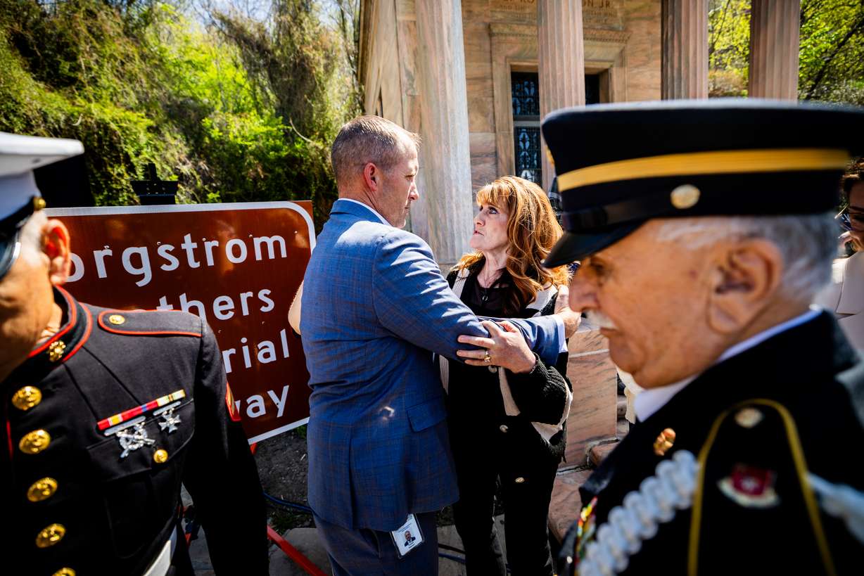 Rep. Thomas Peterson, R-Brigham City, sponsor of HB32, (center left) hugs Deborah Kay Borgstrom Long, a member of the Borgstrom family, (center right), after Gov. Spencer Cox unveils the Borgstrom Brothers Memorial Highway sign at Memory Grove Park in Salt Lake City on Monday.
