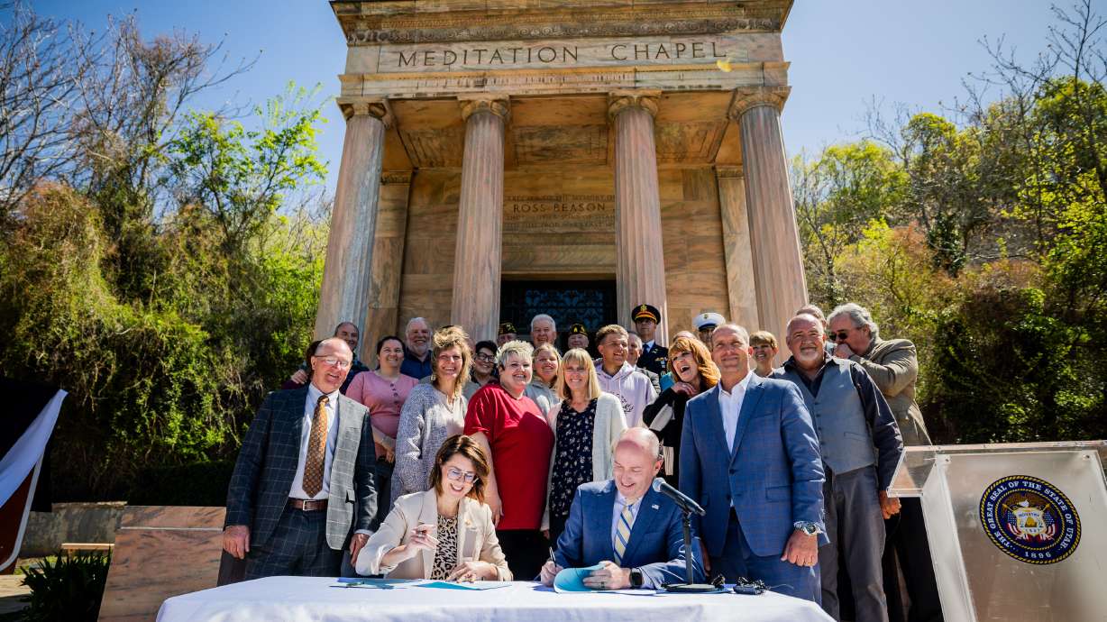 Lt. Gov. Deidre Henderson, left, and Gov. Spencer Cox, right, sign a ceremonial bill to commemorate the passage of HB32 at Memory Grove Park in Salt Lake City on Monday. The designation honors the sacrifice of four brothers during World War II.