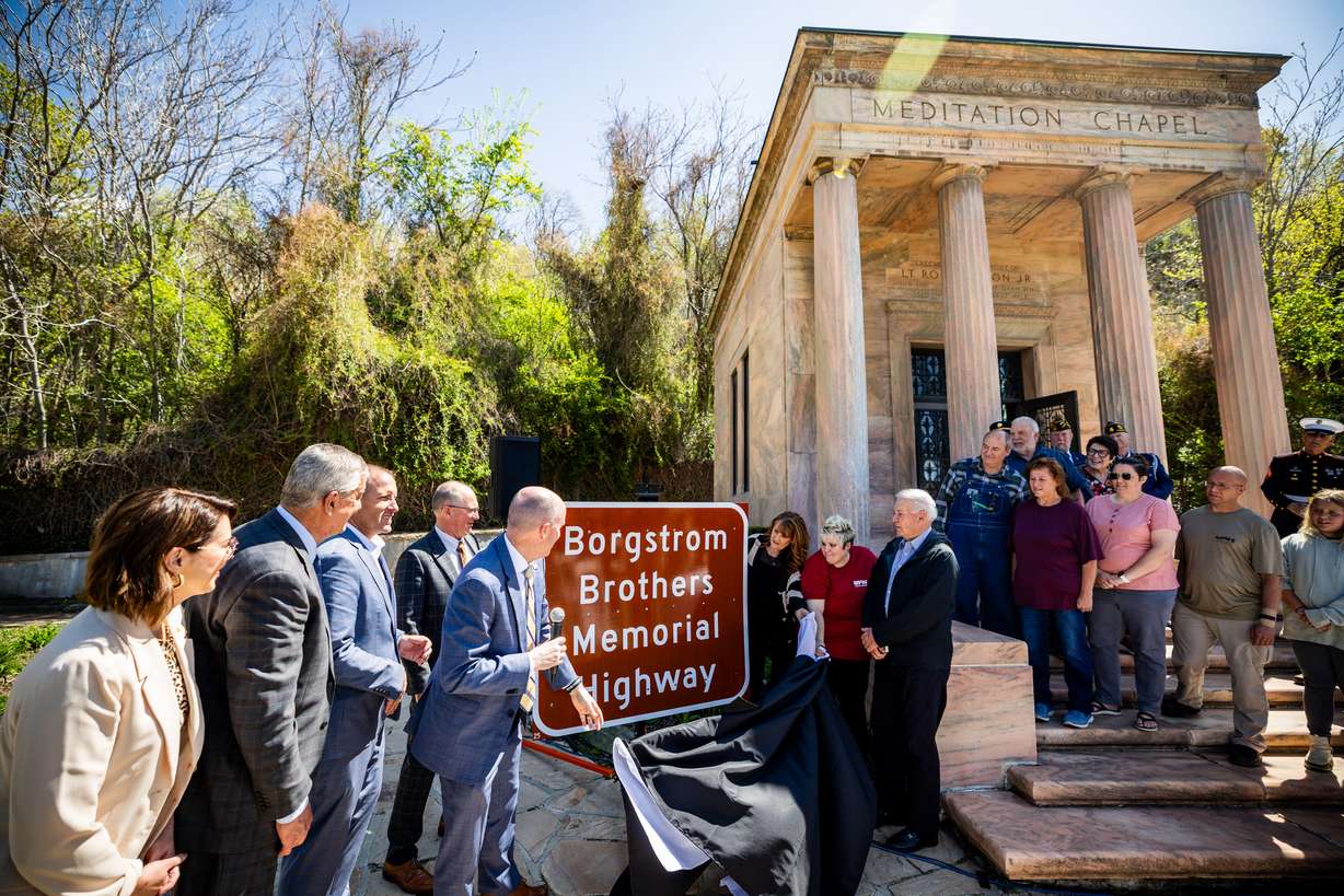 Gov. Spencer Cox unveils the Borgstrom Brothers Memorial Highway sign at a ceremonial bill signing to commemorate the passage of HB32, officially designating Route 102 through Tremonton and Thatcher as the Borgstrom Brothers Memorial Highway at Memory Grove Park in Salt Lake City on Monday. The designation honors the sacrifice of four brothers from the Borgstrom family who gave their lives during World War II.