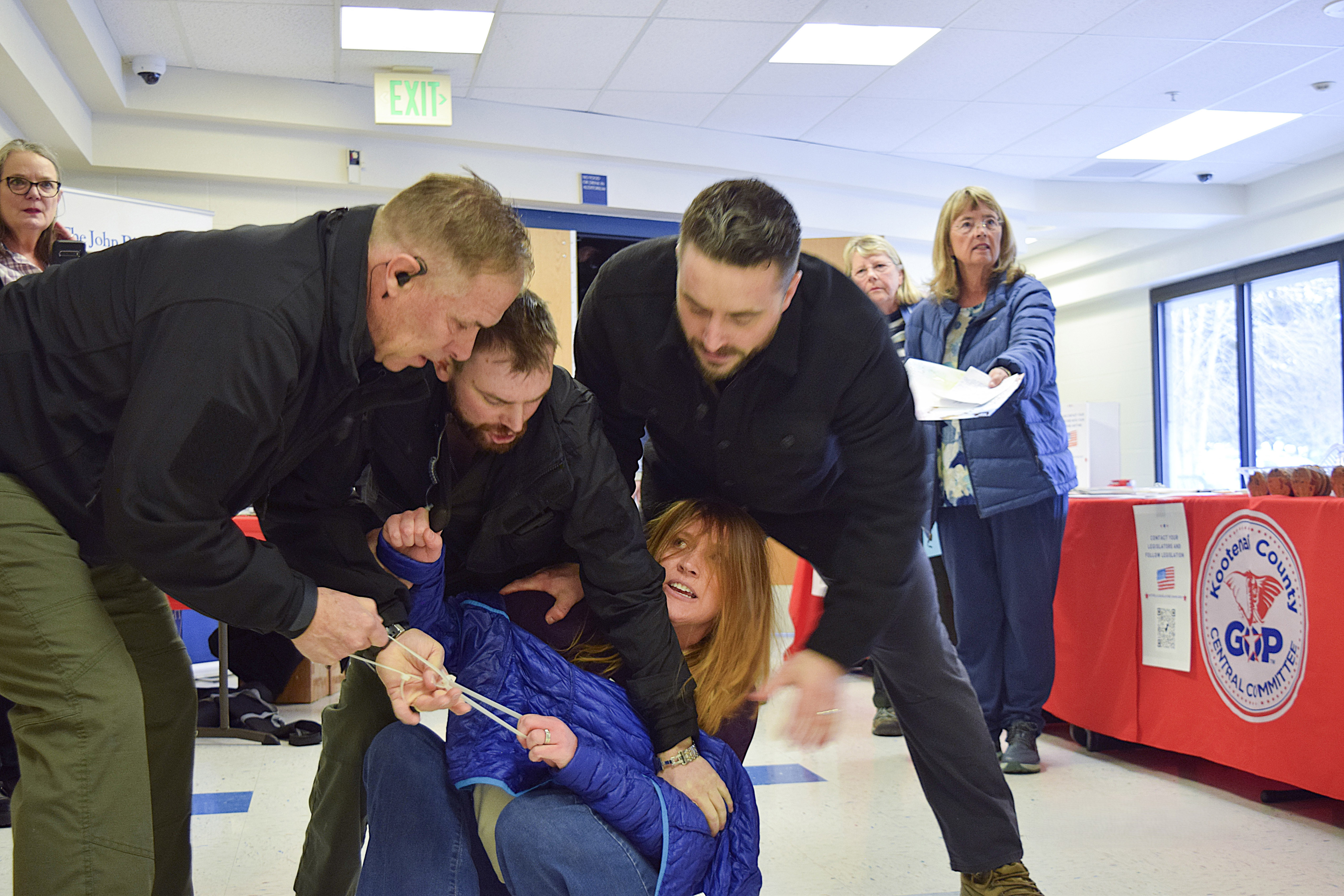Employees of a security firm drag Idaho resident Teresa Borrenpohl out of a town hall meeting on Feb. 22 in Post Falls, Idaho. Prosecutors have filed misdemeanor charges against six men in connection with the forcible removal.
