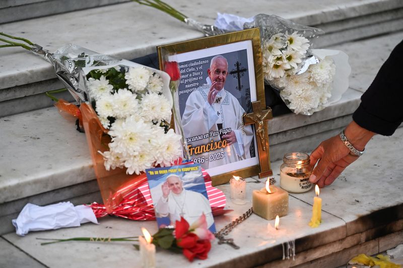 A person leaves a candle in front of a picture of Pope Francis outside the Buenos Aires' Metropolitan Cathedral, following the death of the pontiff, in Buenos Aires, Argentina, Monday.