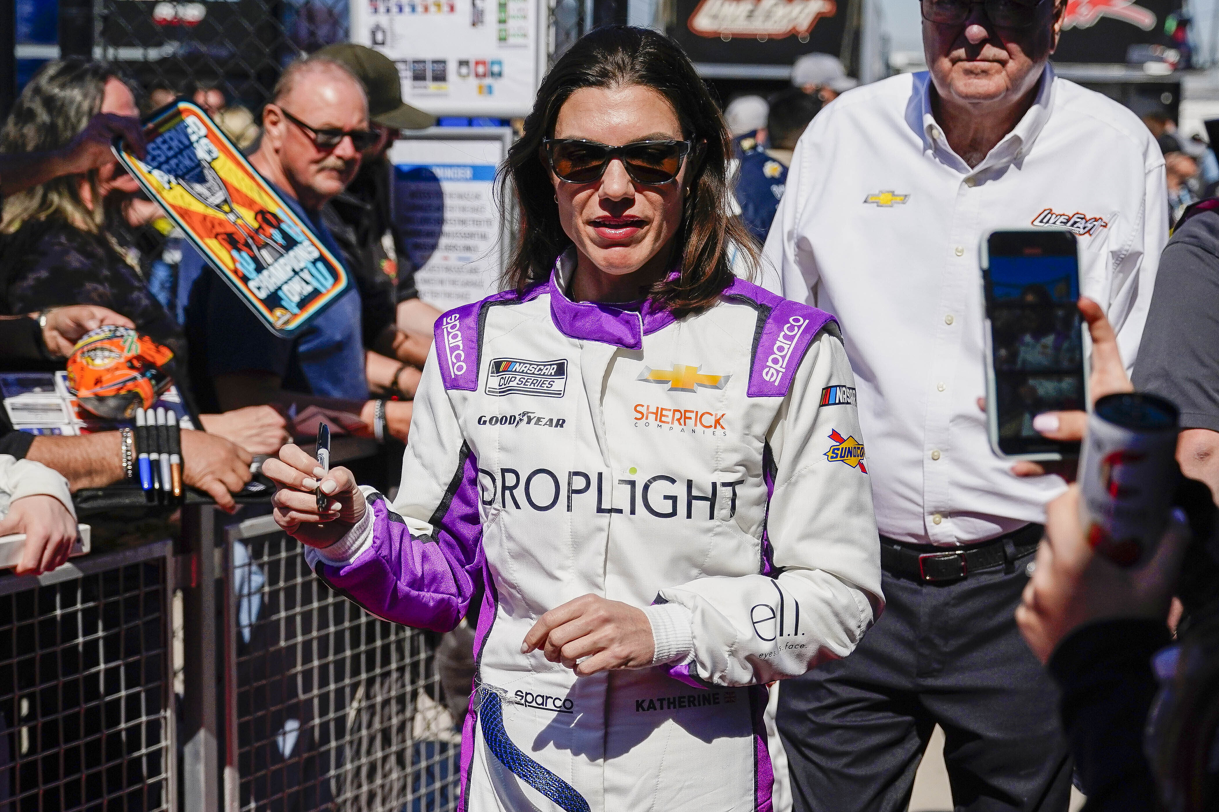 FILE - Driver Katherine Legge signs autographs before the start of a NASCAR Cup Series at Phoenix Raceway, Sunday, March 9, 2025, in Avondale, Ariz.