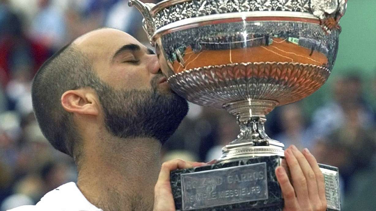 FILE - Andre Agassi of the U.S. kisses the trophy after he defeated Andrei Medvedev of Ukraine 1-6, 2-6, 6-4, 6-3, 6-4 during the men's final tennis match at the French Open at Roland Garros stadium in Paris Sunday, June 6, 1999.