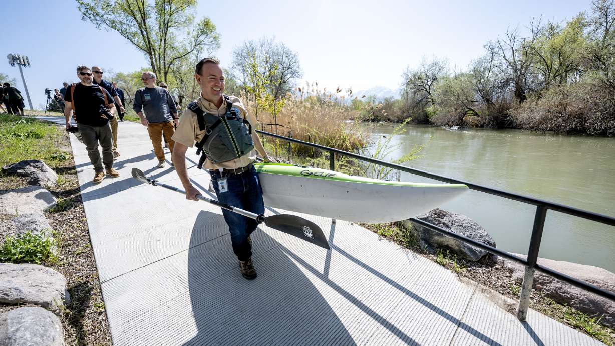 Mike Winder, Millcreek's city manager, carries a kayak down the launch as Millcreek officially opens a new park, trail and boat launch along the Jordan River at 1015 West and 4000 South on Tuesday.