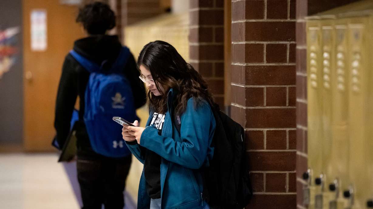 Sarah Valle, 17, uses her phone between classes at Cyprus High School in Magna on Jan. 27, 2023. Congress is looking at cellphone restrictions in schools.