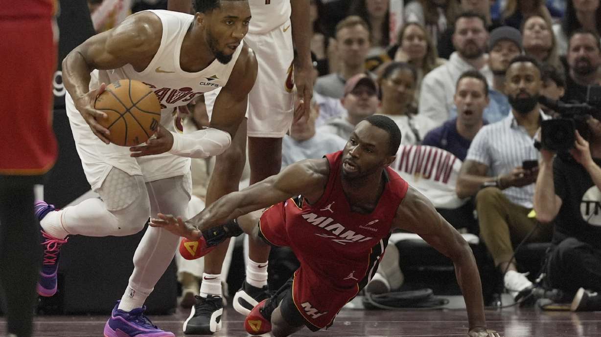 Miami Heat forward Andrew Wiggins, right, reaches for the ball as Cleveland Cavaliers guard Donovan Mitchell (45) heads up the court in the second half in Game 1 of an NBA first-round playoff series, Sunday, April 20, 2025, in Cleveland.