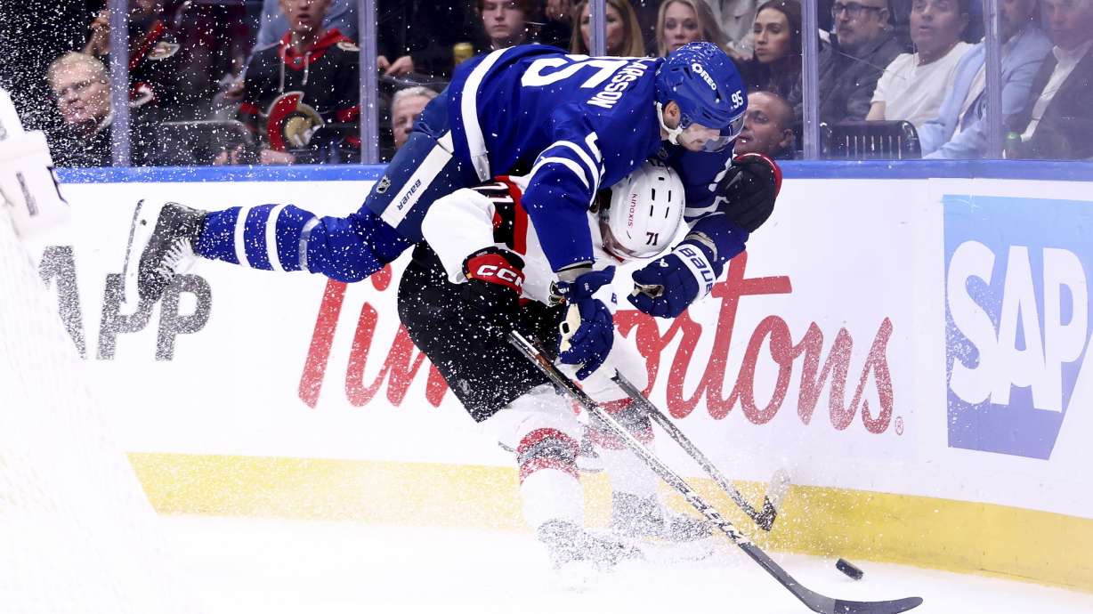 Toronto Maple Leafs' Oliver Ekman-Larsson (95) rides on top of Ottawa Senators' Ridly Greig (71) during the third period of an NHL hockey playoff game in Toronto, on Tuesday, April 22, 2025.