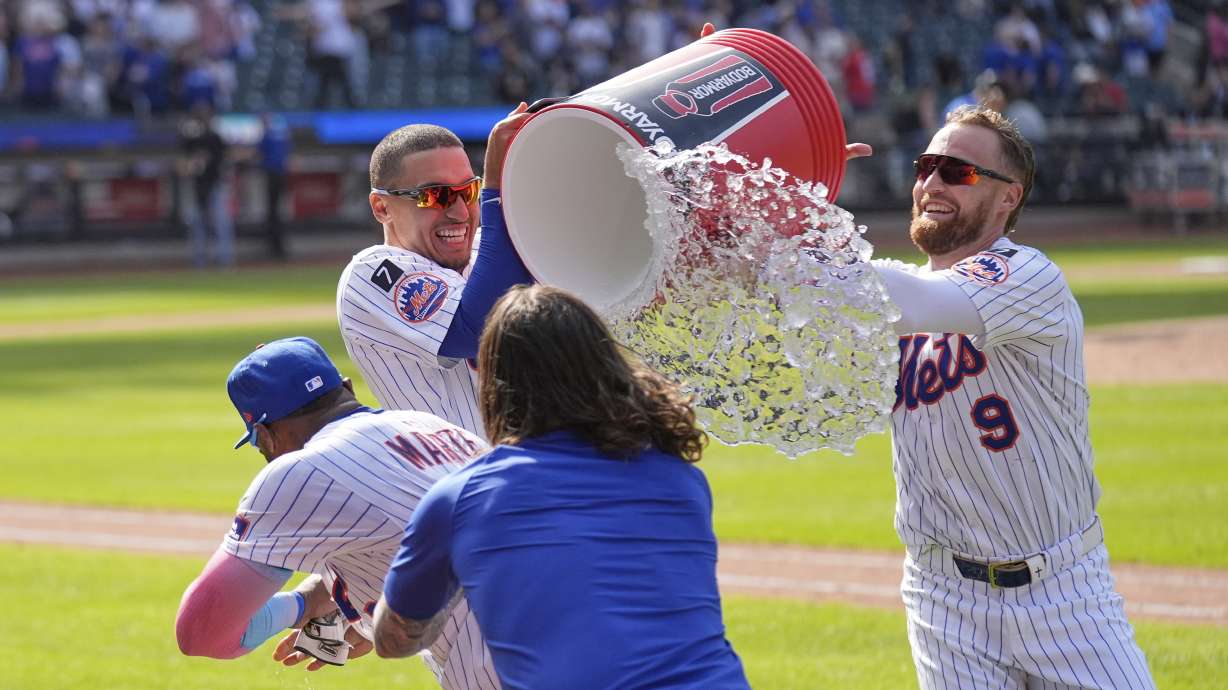 New York Mets' Tyrone Taylor, second from left, and Brandon Nimmo (9), right, try to douse Starling Marte, left, after he hit a walk off single during the tenth inning of a baseball game against the Philadelphia Phillies, Wednesday, April 23, 2025, in New York.