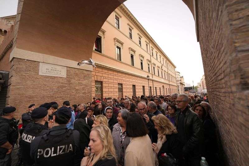 A gull flies above people waiting in St. Peter's Square to pay their respects to the late Pope Francis, who will lie in state at St. Peter's Basilica for three days, at the Vatican, Wednesday.