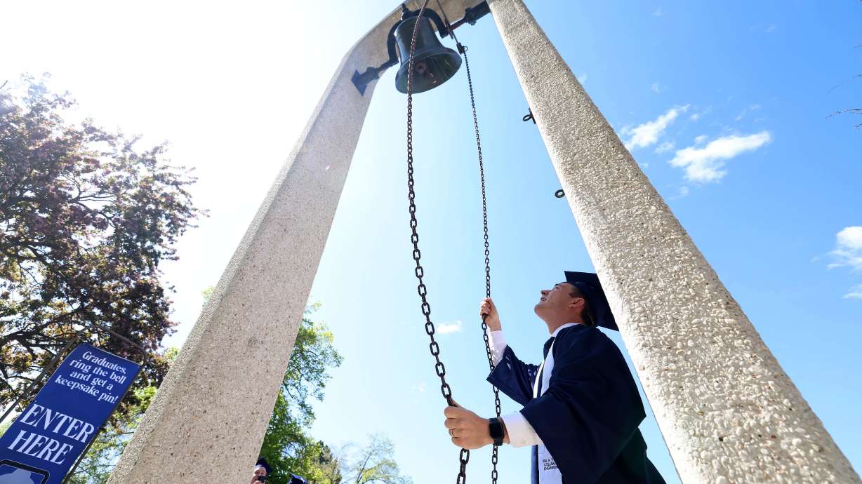 Connor Crandall, graduating with a bachelor’s degree in mechanical engineering, rings an alumni bell outside the Marriott Center after Brigham Young University’s commencement ceremony, held in Provo on Thursday.