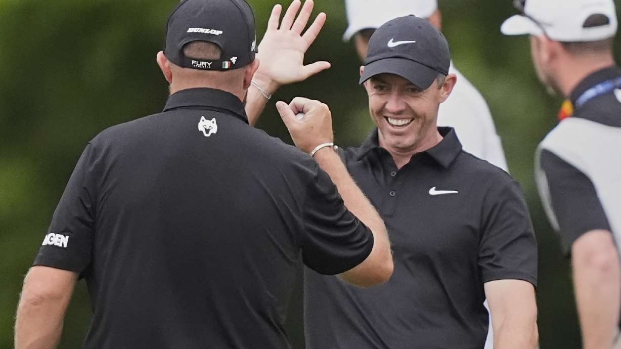 Rory McIlroy, of North Ireland, facing, reacts with teammate Shane Lowry, of Ireland, after Lowry's birdie putt on the 10th hole during the first round of the PGA Zurich Classic golf tournament at TPC Louisiana in Avondale, La., Thursday, April 24, 2025.