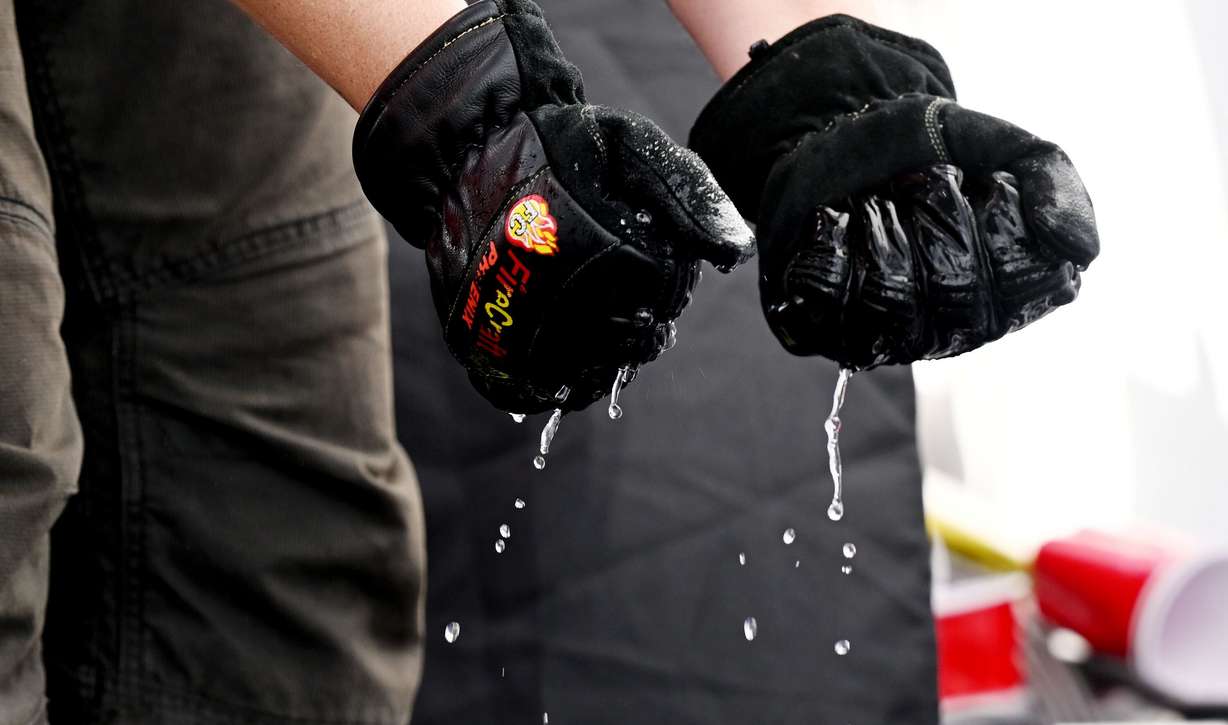 Firefighter Katherine Kaltenbach of the St. Lucie County Fire District in Florida dunks her hands and gloves into water to aid in grip as she competes in the SERVPRO FCL 2025 West Region Classic in the TFT Firefighter Challenge Championship Series, at the Utah State Fairpark in Salt Lake City on Friday.
