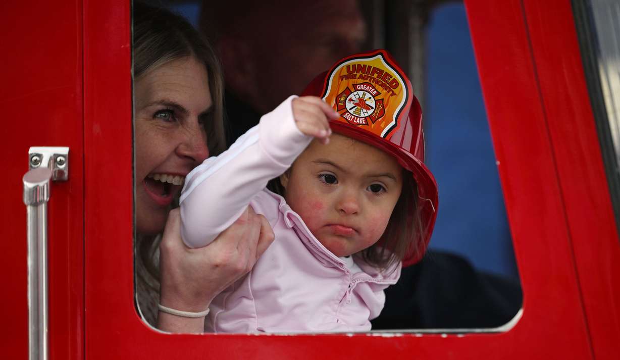 With the help of her mother, Katie Gamero, Everly Gamero waves to the firefighters as she arrives in a special fire truck as she receives her wish from the Make-a-Wish Foundation at a ceremony held before firefighters compete in the SERVPRO FCL 2025 West Region Classic in the TFT Firefighter Challenge Championship Series, at the Utah State Fairpark in Salt Lake City on Friday. Her father, Luis Gamero, siblings Jace and Ashli, and several Disney princess were also there to help celebrate.