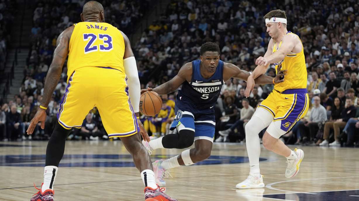 Minnesota Timberwolves guard Anthony Edwards (5) works toward the basket as Los Angeles Lakers forward LeBron James (23) and guard Austin Reaves (15) defend during the first half of Game 3 of an NBA basketball first-round playoff series, Friday, April 25, 2025, in Minneapolis.