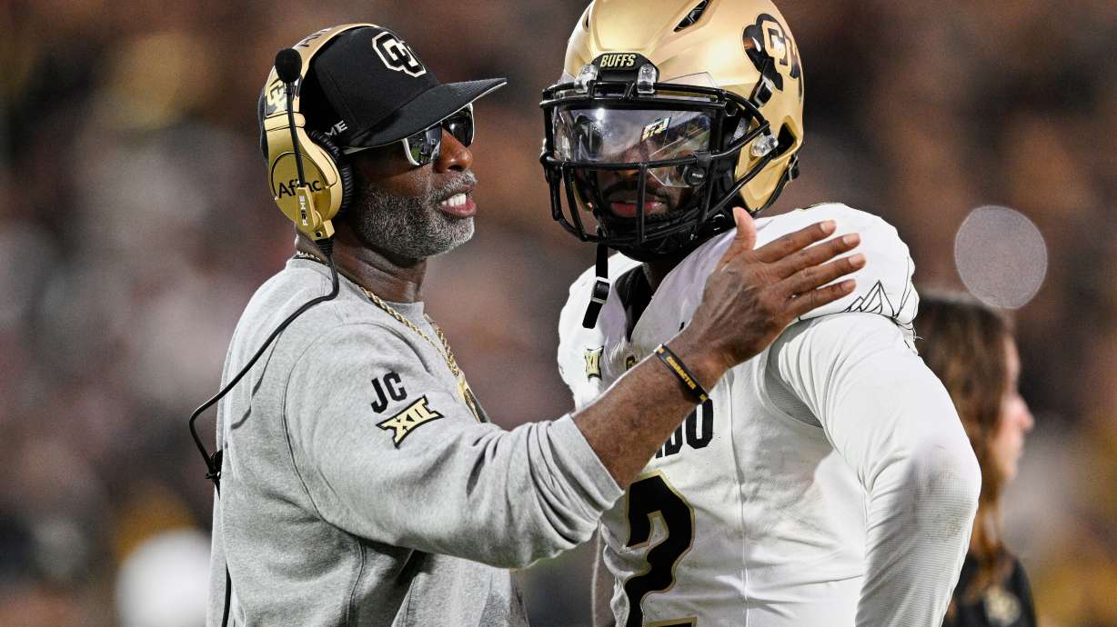 FILE - Colorado head coach Deion Sanders, left, talks with quarterback Shedeur Sanders (2) during a timeout in the second half of an NCAA college football game against Central Florida, Saturday, Sept. 28, 2024, in Orlando, Fla.