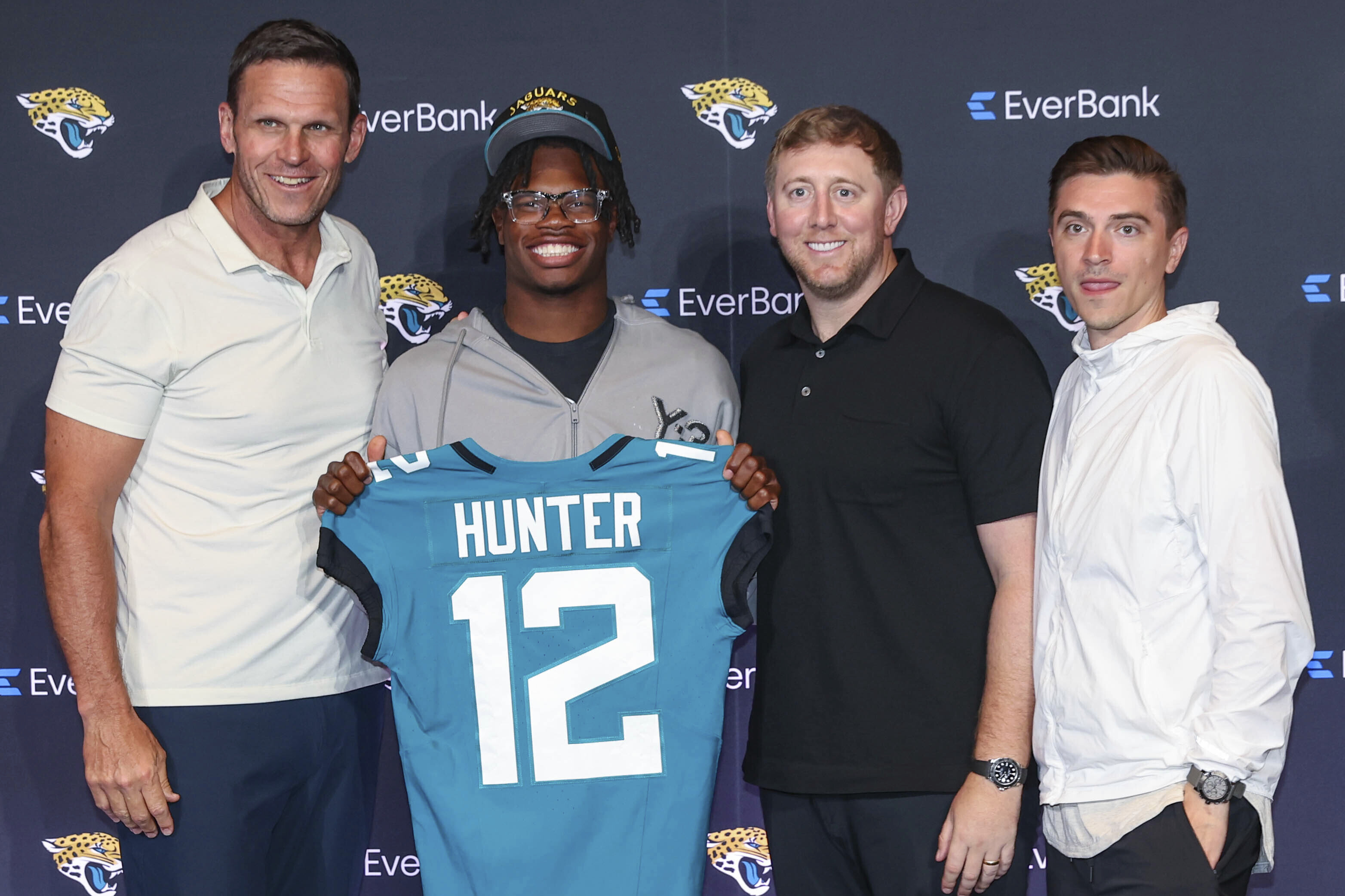 Two-way player Travis Hunter, the Jacksonville Jaguars first round draft pick, second overall, pose with a jersey with general manager James Gladstone, right, head coach Liam Coen, second from right, and executive vice president of football operations Tony Boselli, left, during an NFL football press conference, Friday, April 25, 2025, in Jacksonville, Fla.