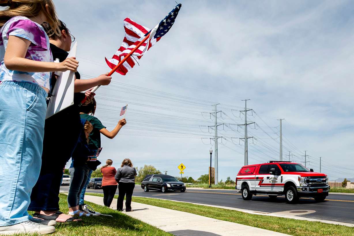 People watch as the funeral procession for the late South Jordan firefighter Corban Summers drives along Clima Drive on their way to Hunter High School in West Valley City for a memorial service on Saturday.