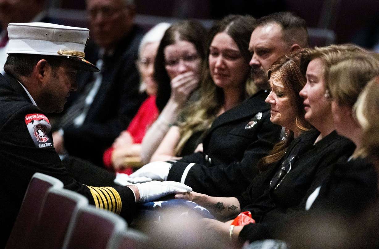 A firefighter presents the flag from the casket to the wife of the late South Jordan firefighter Corban Summers, Kim Summers, during a funeral service for Corban Summers at Hunter High School in West Valley City on Saturday.