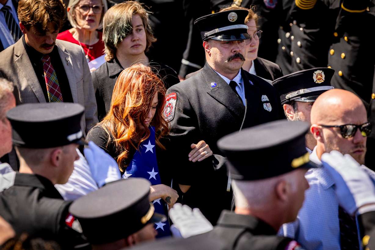 Kim Summers walks with South Jordan Fire Department paramedic Jared Peterson after a memorial service for her late husband, South Jordan firefighter Corban Summers, held at Hunter High School in West Valley City on Saturday.