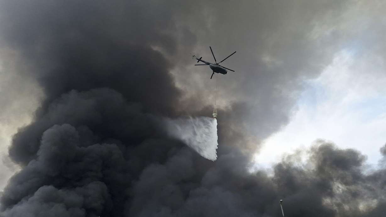 A helicopter drops water on the fire, Sunday after a massive explosion and fire rocked a port near the southern port city of Bandar Abbas, Iran on Saturday.