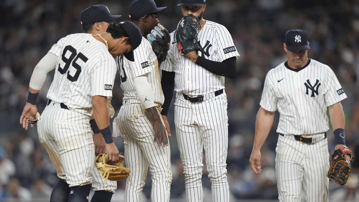 New York Yankees pitcher Devin Williams, center, talks to Anthony Volpe as they huddle with teammates during the ninth inning of a baseball game against the Toronto Blue Jays Friday, April 25, 2025, in New York.