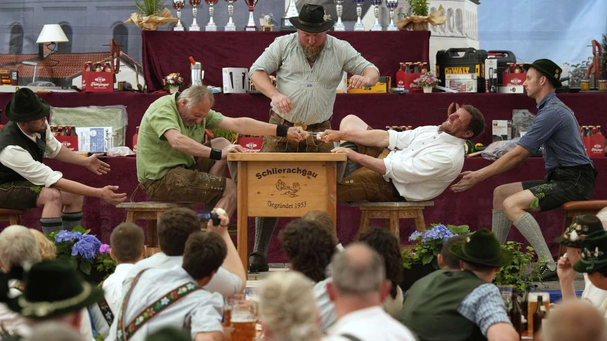 Men dressed in traditional clothes try to pull the opponent over the table at the German Championships in Fingerhakeln or finger wrestling, in Pang, near Rosenheim, Germany, Sunday, April 27, 2025.