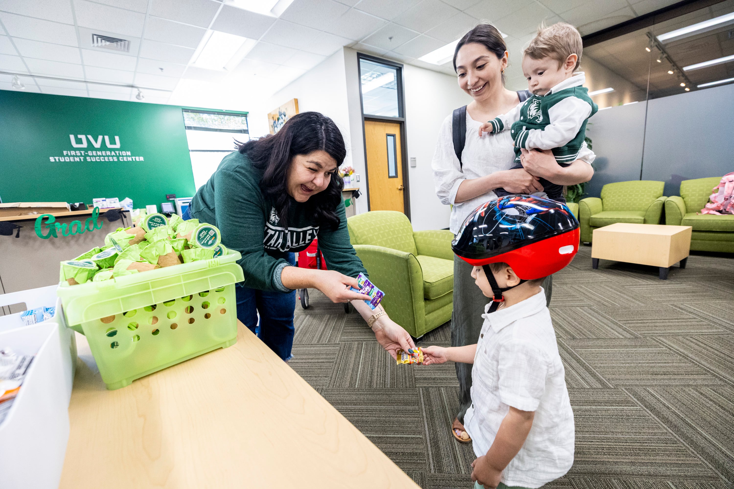 Whitney Dawe, program coordinator at the First-Generation Student Success Center, gives a snack to Jason Jackson, 2, as he’s joined by his mom, Michelle Jackson, a rising senior studying accounting, and his brother, Damian, 9 months, on the campus of Utah Valley University in Orem on Tuesday, April 29, 2025.