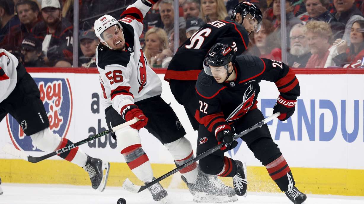 Carolina Hurricanes' Logan Stankoven (22) gathers in the puck around teammate Sean Walker (26) and in front of New Jersey Devils' Erik Haula (56) during the third period of Game 5 of an NHL hockey Stanley Cup first-round playoff series in Raleigh, N.C., Tuesday, April 29, 2025.