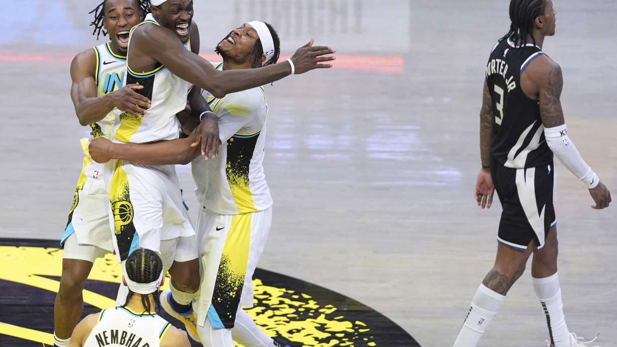 Indiana Pacers teammates Aaron Nesmith, left, Pascal Siakam, center, and Myles Turner, right, celebrate the team's win after overtime in Game 5 of an NBA basketball first-round playoff series as Milwaukee Bucks guard Kevin Porter Jr. (3) walks off the court in Indianapolis, Tuesday, April 29, 2025.