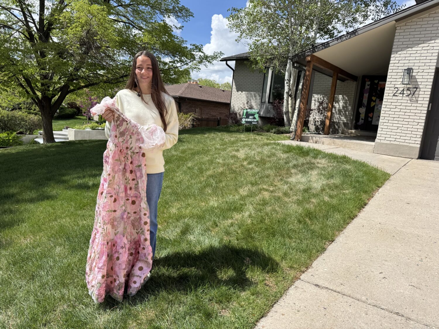 Sixteen-year-old Zoey Hendrickson stands with replacement prom dress Sandy firefighters helped her find.