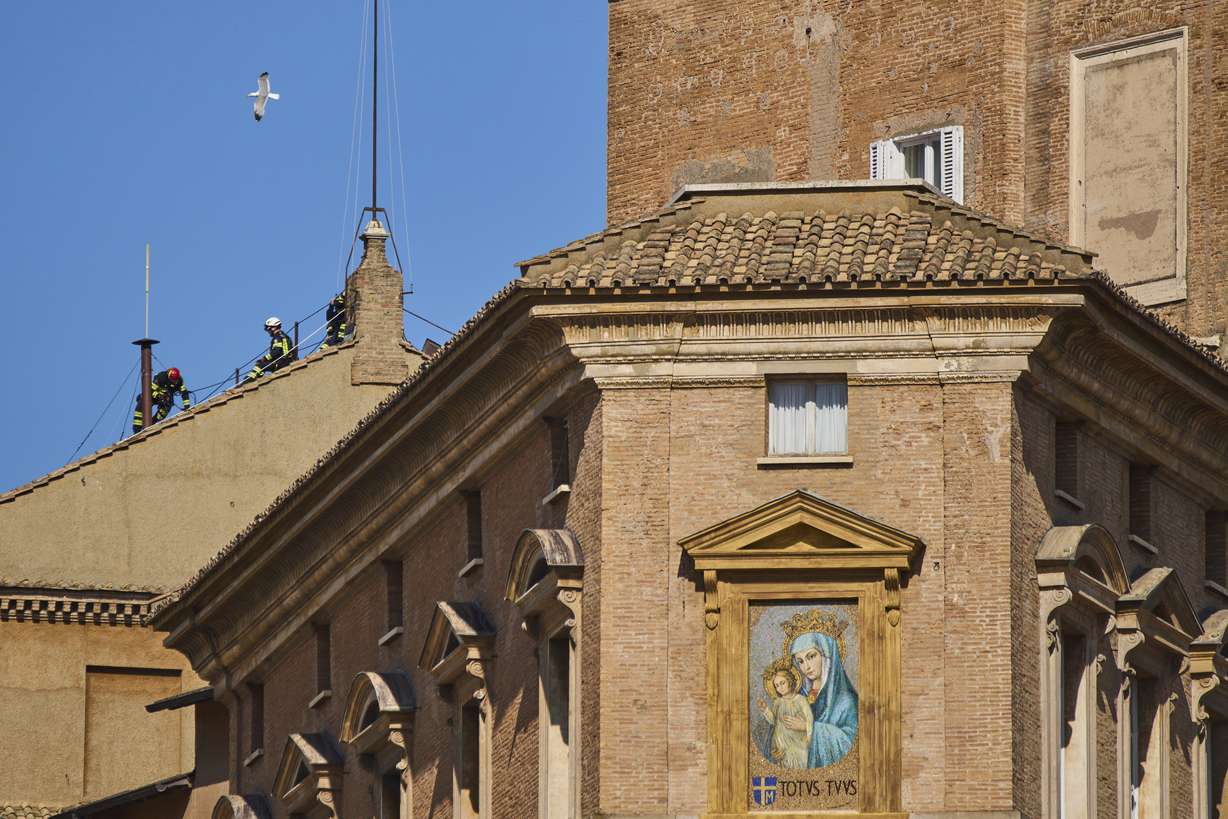 Firefighters place the chimney on the roof of the Sistine Chapel, where cardinals will gather to elect the new pope, at the Vatican, Friday.