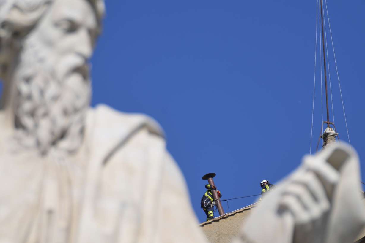 Firefighters place the chimney on the roof of the Sistine Chapel, where cardinals will gather to elect the new pope, at the Vatican, Friday.