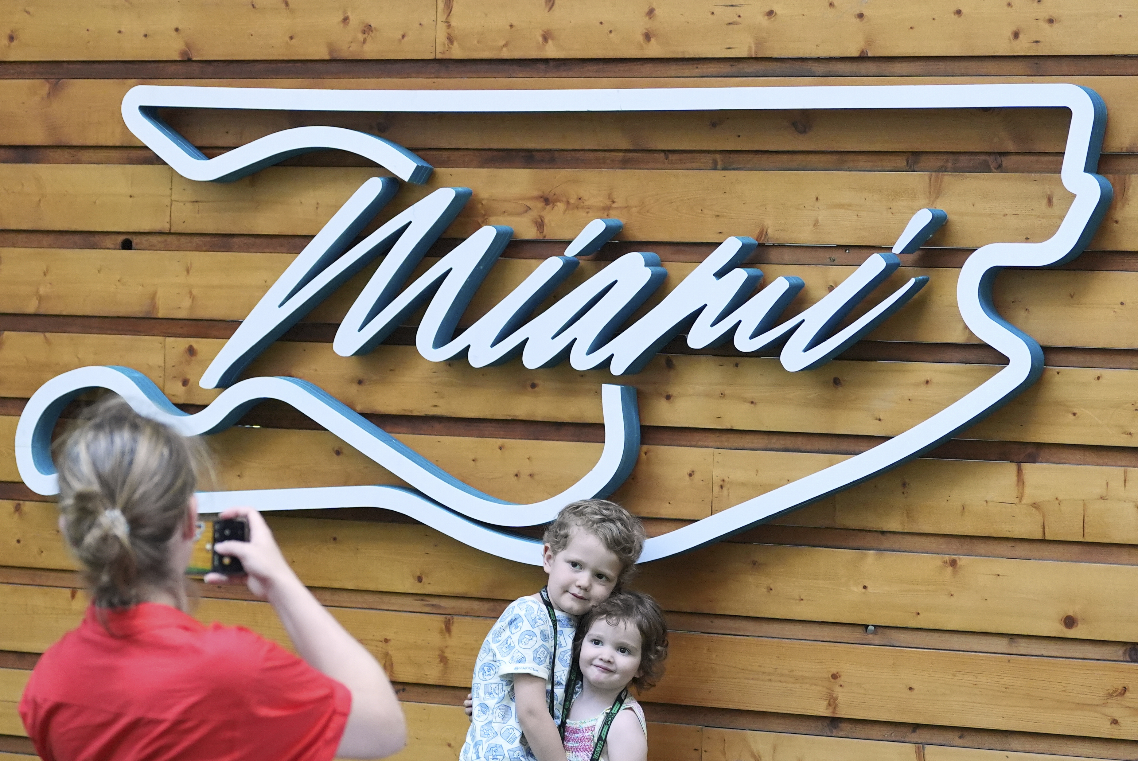 Aaron Mart, 4, and his sister Eloise, 2, whose father is an engineer for the Red Bull team, have their photo taken by their mother Anne Bachelay in front of a Formula One Miami Grand Prix auto race logo in the shape of the track, Thursday, May 1, 2025, in Miami Gardens, Fla.