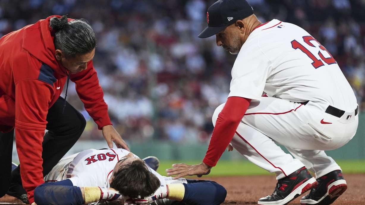 Boston Red Sox's Triston Casas lies on the field while comforted by manager Alex Cora (13) after an apparent injury during the second inning of a baseball game against the Minnesota Twins at Fenway Park, Friday, May 2, 2025, in Boston.