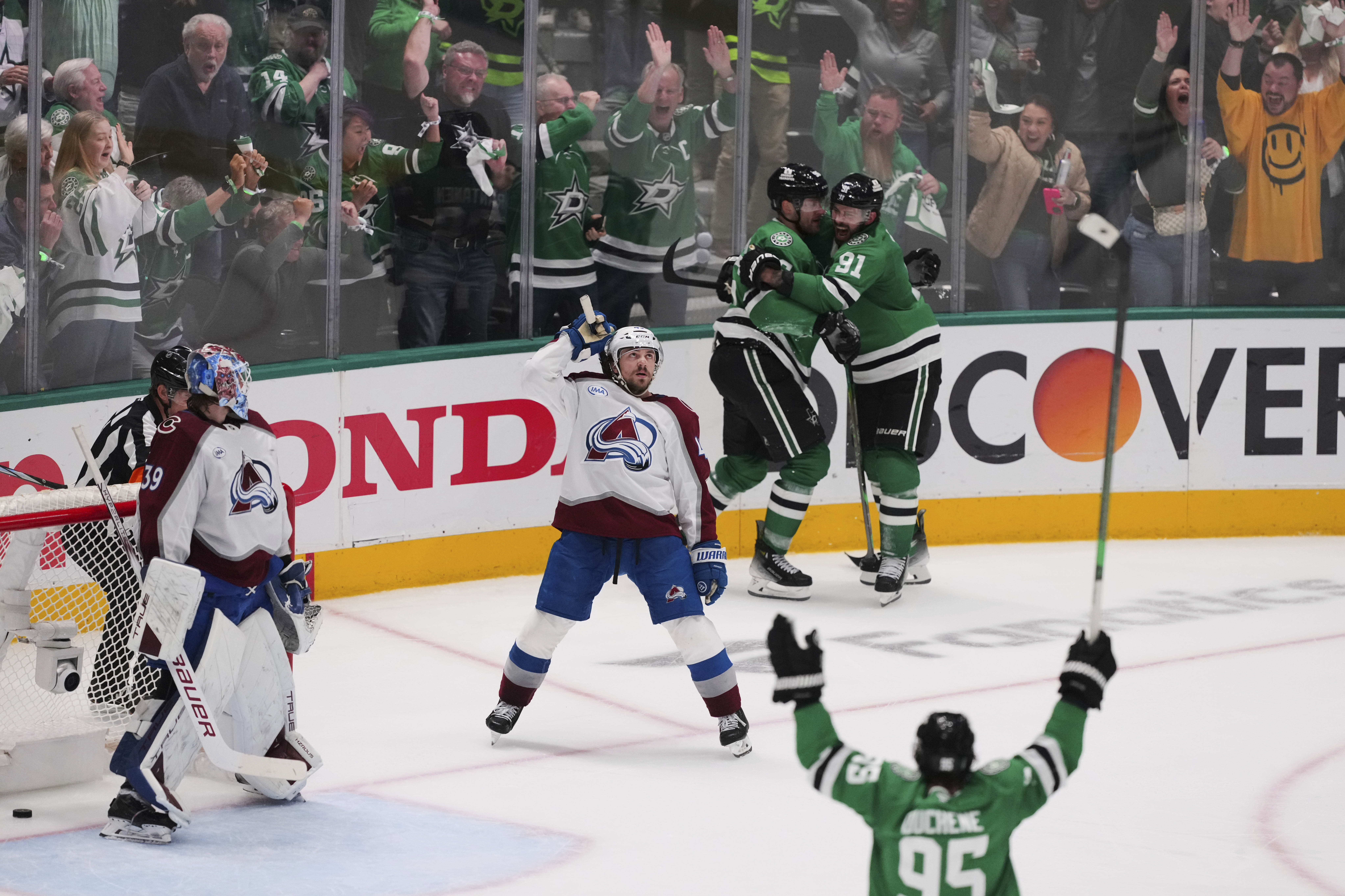 Colorado Avalanche goaltender Mackenzie Blackwood (39) and Samuel Girard, center, look on as the Dallas Stars celebrate a goal scored by Dallas Stars' Mikko Rantanen, rear, in the third period in Game 7 of a first-round NHL hockey playoff series Saturday, May 3, 2025, in Dallas.