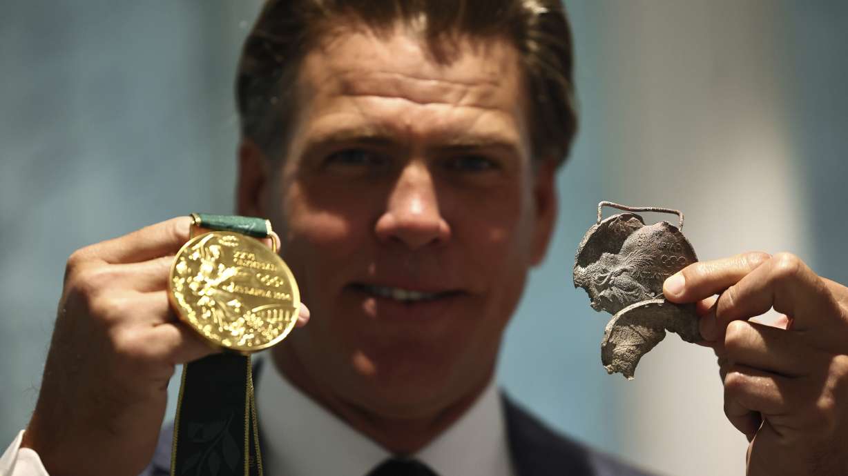 American swimmer Gary Hall Jr. holds an original medal from Atlanta 1996, that melted during the wildfires in Los Angeles that destroyed his home earlier this year, while holding a replica of the Olympic medal that IOC President Thomas Bach presented to him during a ceremony at the Olympic House in Lausanne, Switzerland, Monday, May 5, 2025.