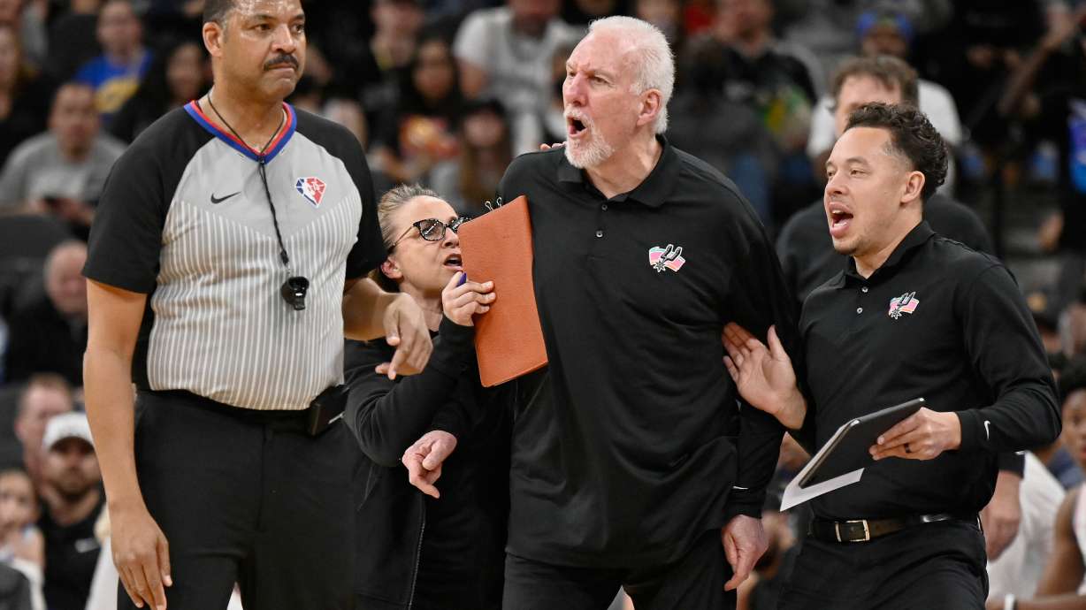 FILE - San Antonio Spurs head coach Gregg Popovich, second from right, yells at referee Bennie Adams, left, while being restrained by Spurs assistant coaches Mitch Johnson, right, and Becky Hammon during the first half of an NBA basketball game against the New Orleans Pelicans on Friday, March 18, 2022, in San Antonio.