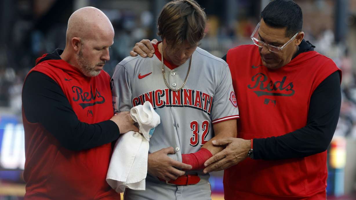 Cincinnati Reds outfielder Tyler Callihan (32) is helped off the field after colliding with the wall during the third inning of a baseball game against the Atlanta Braves, Monday, May 5, 2025, in Atlanta.