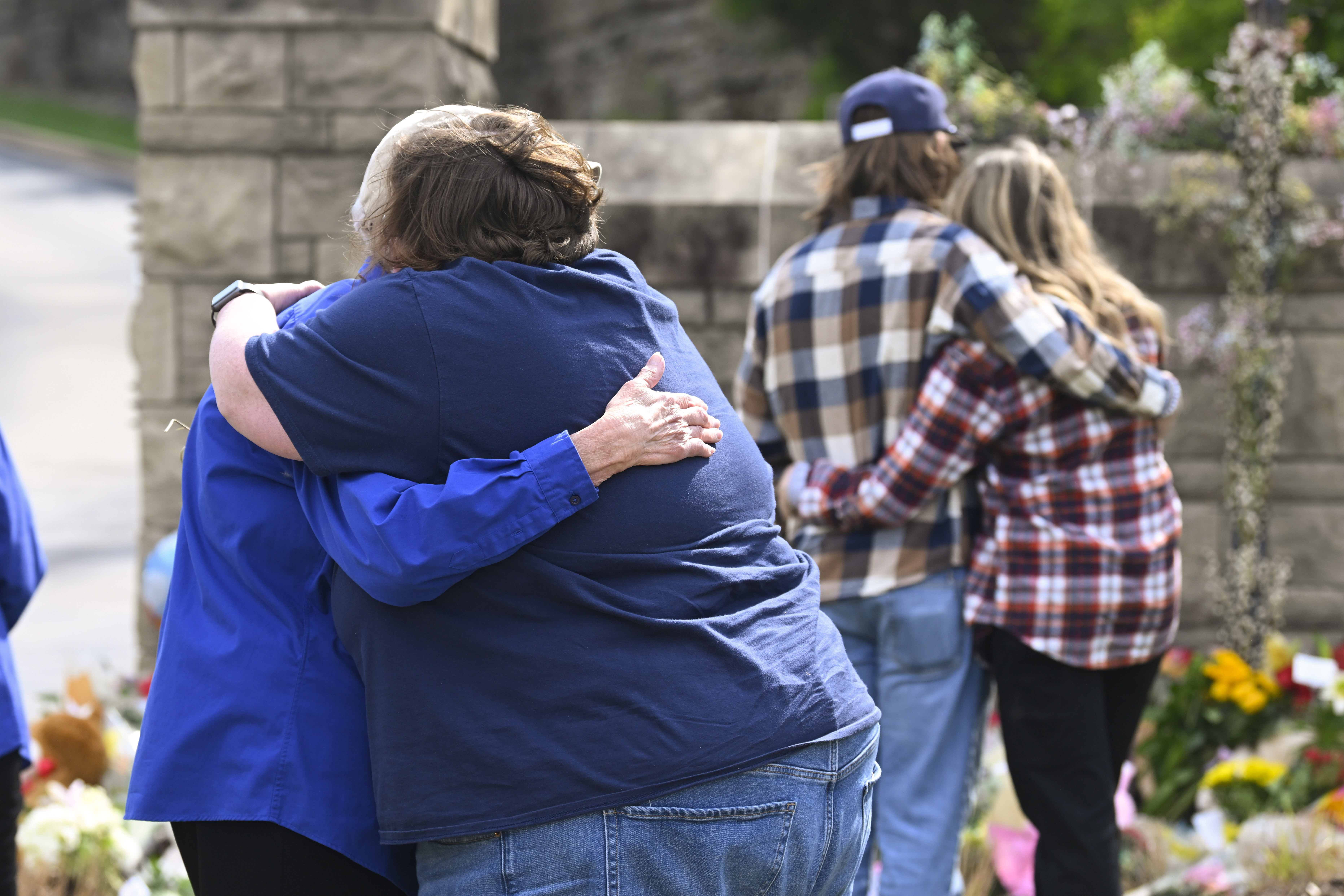 People console each other at an entry to Covenant School, March 28, 2023, in Nashville, Tenn. A former Nashville police lieutenant was arrested Tuesday on charges of taking case files from the Nashville shooting.