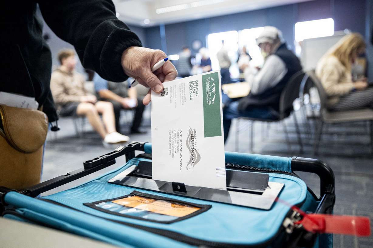 A voter drops their ballot in a drop box at the Utah County Health and Justice Building in Provo on Oct. 30, 2024.