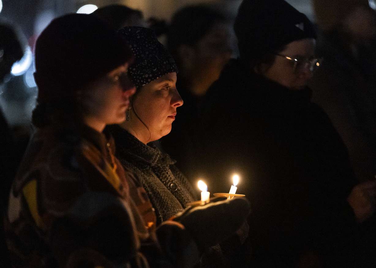 Isa Empey, left, and Haley Kline, center, both hold vigil candles during the annual Homeless Persons’ Memorial Vigil in Pioneer Park in Salt Lake City on Dec. 19, 2024.