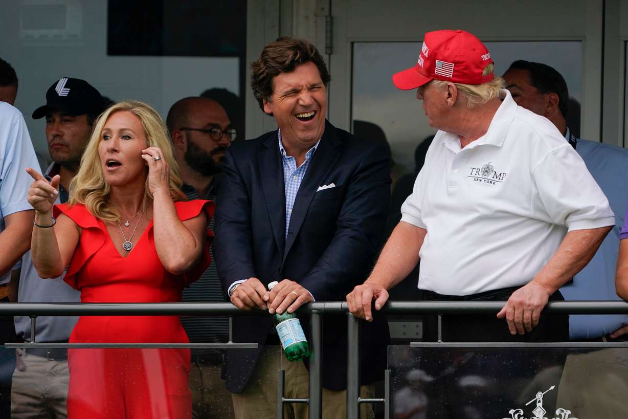 U.S. Rep. Marjorie Taylor Greene, left, Tucker Carlson, center, and former President Donald Trump, right, react during the final round of the Bedminster Invitational LIV Golf tournament in Bedminster, N.J., Sunday, July 31, 2022.